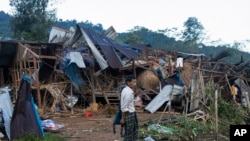 FILE - A man looks at homes destroyed by airstrikes in a refugee camp in Laiza, Myanmar, on Oct. 10, 2023. 