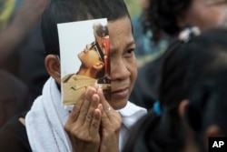 A mourner holds a portrait of the late King Bhumibol Adulyadej during his funeral procession and royal cremation ceremony in Bangkok, Thailand, Oct. 26, 2017.
