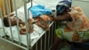 Hassana Ousmane rests her head against the bed where her 21-month-old daughter, Zeinab, suffering from malaria, rests at the Princess Marie Louise Children's Hospital in Accra, Ghana, April 25, 2012.