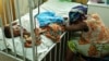 Hassana Ousmane rests her head against the bed where her 21-month-old daughter, Zeinab, suffering from malaria, rests at the Princess Marie Louise Children's Hospital in Accra, Ghana, April 25, 2012.