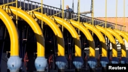 FILE - A worker checks pipes at a gas compressor station on the Yamal-Europe pipeline near Nesvizh, some 130 km (81 miles) southwest of Minsk, Dec. 29, 2006.