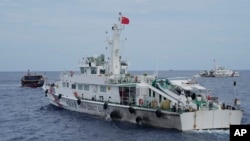 FILE - A Chinese coast guard ship tries to block the way of a Philippine supply boat, left, as it heads towards Second Thomas Shoal, at the disputed South China Sea on Aug. 22, 2023. Philippine officials on Sept. 25 condemned a floating barrier laid by Chinese vessels