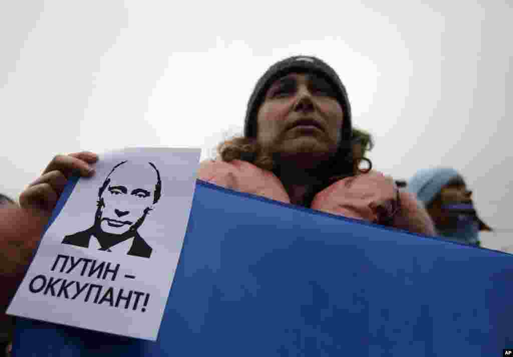 Seorang perempuan memegang poster bertuliskan &quot;Putin adalah Penjajah&quot; dalam kampanye anti-pemecahan Ukraina di Simferopol, Krimea, Ukraina (11/3). (AP/Darko Vojinovic)