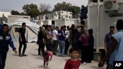 FILE - Migrants and refugees wait outside UNHCR offices for their papers, inside the camp of Moria on Lesbos, Greece.