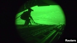A still image captured from the U.S. Central Command night vision video footage shows an Air Force personnel retrieving straps after the U.S. military airdrop of food and water for thousands of Iraqi citizens threatened by the Islamic State of Iraq and th