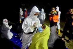 Seorang petugas medis mengambil sampel usap hidung dari seorang wanita Rohingya saat tes virus corona untuk etnis Rohingya yang terdampar di Pulau Idaman, Aceh Timur, 4 Juni 2021. (Foto: AP)