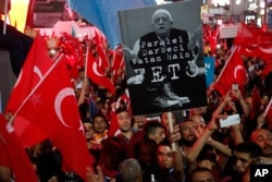 FILE - Supporters of Turkish President Recep Tayyip Erdogan wave their national flags and hold a portrait of Fethullah Gulen, a U.S.-based Muslim cleric, with Turkish words that read: "the Coup nation traitor, FETO" (Feto is the nickname of Fethullah Gulen), during a pro-government rally at Kizilay main square, in Ankara, Turkey, July 20, 2016.