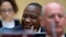 FILE - Kenya's President Uhuru Kenyatta, sitting with his defense team, smiles during an October hearing before the International Criminal Court in The Hague, Netherlands.