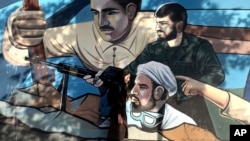 FILE- An Iranian woman walks past a mural portraying Iranians' solidarity against their enemies, painted on the wall of a government building at the Felestin (Palestine) Sq. in downtown Tehran, July 30, 2018. 