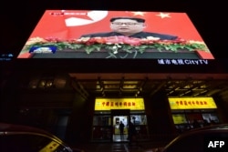 News video footage of North Korean leader Kim Jong Un during his meeting with China's President Xi Jinping is seen on a large screen above a restaurant in Beijing on March 28, 2018.