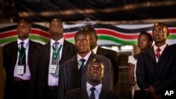 Security and bodyguards of the election commission chairman stand as he delivers a statement to the media, at the National Election Center