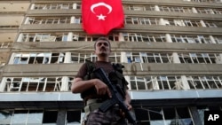 FILE - A Turkish special forces policeman stands guard in front of a damaged building inside the special forces policemen base, which was attacked during the failed military coup earlier this month, in Ankara, Turkey, July 19, 2016. Despite the chaos within the Turkish military, the PKK Kurdish rebel group has not launched any major attacks.