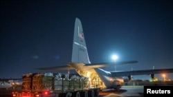 Angkatan Udara AS memuat paket-paket bantuan makanan dan minuman untuk rakyat Palestina di Gaza ke adalam pesawat C-130U Super Hercules dari lokasi yang tidak disebutkan di barat daya Asia, Jumat, 1 Maret 2023. (Foto: US Air Force via Reuters)