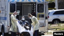 Emergency Medical Technicians lift a patient that was identified to have coronavirus disease into an ambulance while wearing protective gear, in New York City, New York, March 26, 2020.
