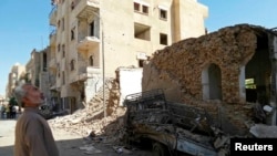 FILE - A man looks at damage at a site hit by what activists said was an airstrike by forces loyal to Syria's President Bashar al-Assad in Raqqa, Syria.