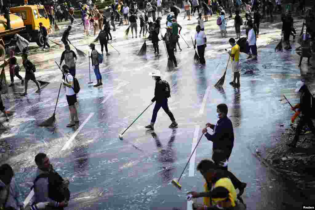 Anti-government protesters sweep the street around the Democracy Monument after weeks of protesting and days of clashes with police in Bangkok's city center, Dec. 4, 2013.
