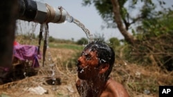 An Indian man takes bath under the tap of a water tanker on a hot day in Ahmadabad, India, May 21, 2015. 