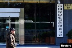 Seorang pria berjalan melewati gedung perkantoran China Insurance Regulatory Commission (CIRC) di Beijing, China 18 November 2017. (REUTERS/Stringer)