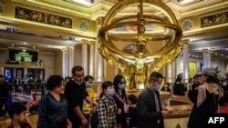 Para pengunjung sebuah resor hotel kasino di Makau mengenakan masker penutup mulut, 22 Januari 2020. (Foto: AFP)