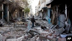 FILE - A Kurdish fighter walks through rubble in Kobani, Syria.