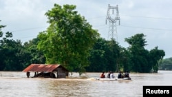 FILE - Volunteers ride a boat through a flooded area, searching for stranded people following the impact of Typhoon Yagi in Taungnoo city, Myanmar, September 17, 2024. 