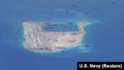 FILE - Chinese dredging vessels are purportedly seen around Fiery Cross Reef in the disputed Spratly Islands in the South China Sea in this image from video taken by a P-8A Poseidon surveillance aircraft provided by the U.S. Navy, May 21, 2015. 