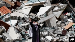 A Palestinian woman reacts near the rubble of a building housing The Associated Press, broadcaster Al-Jazeera and other media outlet, in Gaza City. The building was destroyed by an Israeli airstrike on Saturday.