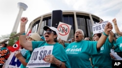 FILE - Lydia Balderas, left, and Merced Leyua, right, join others as they protest against a new sanctuary cities bill outside the federal courthouse in San Antonio, June 26, 2017. 