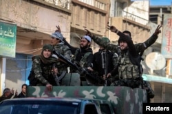 FILE - Fighters of the Kurdish People's Protection Units (YPG) carry their weapons along a street in the Syrian Kurdish city of Qamishli, in celebration after it was reported that Kurdish forces took control of the Syrian town of Tel Hamis, Feb. 27, 2015.