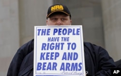FILE - John Doll, of Renton, Wash., holds a sign that reads "The people have the right to keep and bear arms" during a gun rights rally at the Capitol in Olympia, Wash.