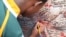 A young boy tried to squeeze his name onto a Mandela poster outside his home in Soweto, South Africa. (Hannah McNeish for VOA)