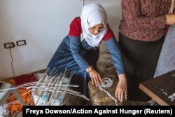 Jordanian mother of seven, Dallal Sarhan, plaits and weaves newspapers to construct a side table, at an up-cycling workshop in Irbid city, northern Jordan, May 9, 2018.