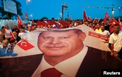 Pro-government demonstrators hold a giant Turkish national flag during a march towards the Asian side of the Bosphorus Bridge in Istanbul, Turkey, July 21, 2016.