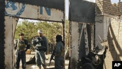 Afghan security forces secure an entrance next to the wreckage of a suicide bomber's vehicle at a UN compound in Herat, west of Kabul, Afghanistan, 23 Oct 2010