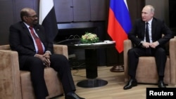 FILE - Russian President Vladimir Putin talks with Sudan's President Omar al-Bashir during their meeting in the Black Sea resort of Sochi, Russia, Nov. 23, 2017.