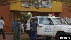 People walk in front of the entrance of Donka Hospital, where victims of the ebola disease are being treated, in Conakry March 28, 2014.