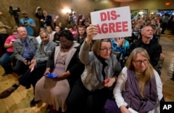 Constituents of Congressman Dave Brat, R-Va., hold signs as he answers questions during a town hall meeting with the congressman in Blackstone, Va., Feb. 21, 2017.