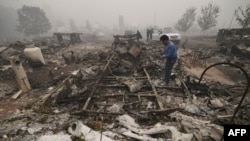 Marcelino Maceda looks for items in the remains of his mobile home after a wildfire swept through the RV park destroying multiple homes in Estacada, Oregon, Sept. 12, 2020. 
