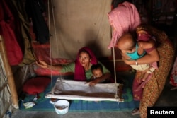 Rohingya refugee women arrange a cradle for a child in their makeshift tent in the Balukhali refugee camp in Cox's Bazar, Bangladesh, Aug. 23, 2018.
