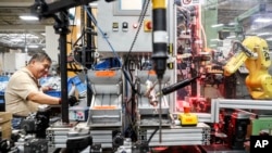 In this Thursday, May 25, 2017 photo, an assembly line laborer works across from a collaborative robot, right, at the Stihl Inc. manufacturing facility in Virginia Beach, Va. (AP Photo/John Minchillo)