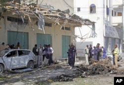 FILE - Somali soldiers stand near the wreckage after a car bomb detonated in Mogadishu, Somalia, Dec. 19, 2015.