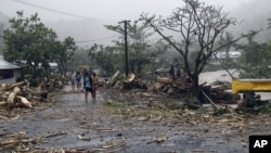 FILE - People walk through debris in Samoa's capital Apia, Dec. 14, 2012, after cyclone Evan ripped through the South Pacific island nation. 