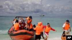 FILE - Chinese tourists disembark from an inflatable boat upon arrival in Quanfu island, a Paracels of Sansha prefecture of China's Hainan province. 