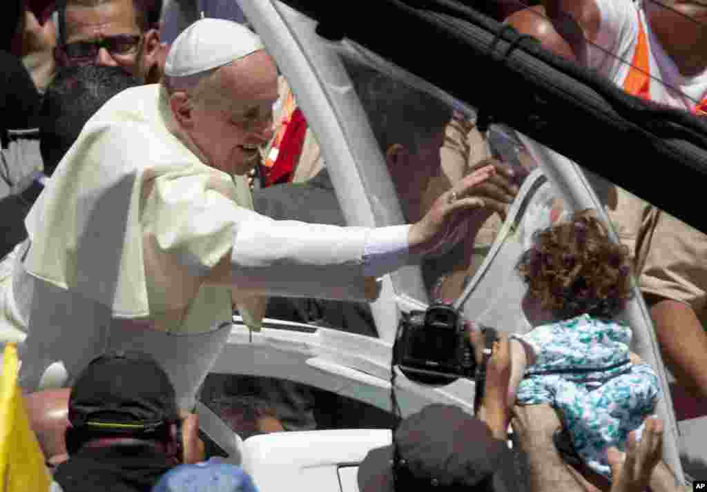 Pope Francis reaches to a girl after a mass in Bethlehem.