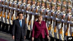 Chinese Premier Li Keqiang, left walks with German Chancellor Angela Merkel during a welcome ceremony held outside the Great Hall of the People in Beijing, China, Thursday, Oct. 29, 2015.
