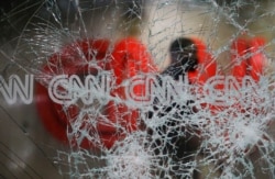 A security guard walks behind shattered glass at the CNN building at the CNN Center in the aftermath of a demonstration against police violence on May 30, 2020, in Atlanta.