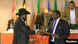South Sudan's President Salva Kiir (front L) and rebel commander Riek Machar exchange documents in Addis Ababa on Monday, Feb. 2, 2015 after agreeing to establish a transitional government.