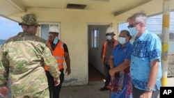 New Zealand High Commissioner Peter Lund, right, and military personnel stand on a dock in Nuku'alofa, Tonga, Jan. 21, 2022 after receiving a New Zealand ship that brought provisions.