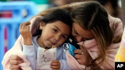 A woman and child embrace under a blanket on the pier, May 13, 2021, in Santa Monica, Calif. 