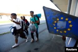 Migrants pass near a phone booth as they cross the border on feet from Austria to Freilassing, Germany Sept. 16, 2015.